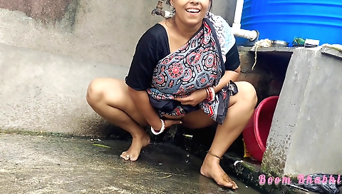 Indian woman in bikini is standing on her head on the lawn